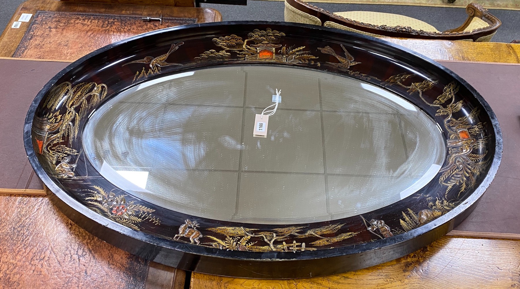 An early 20th century oval chinoiserie lacquered oval wall mirror, width 117cm, height 78cm